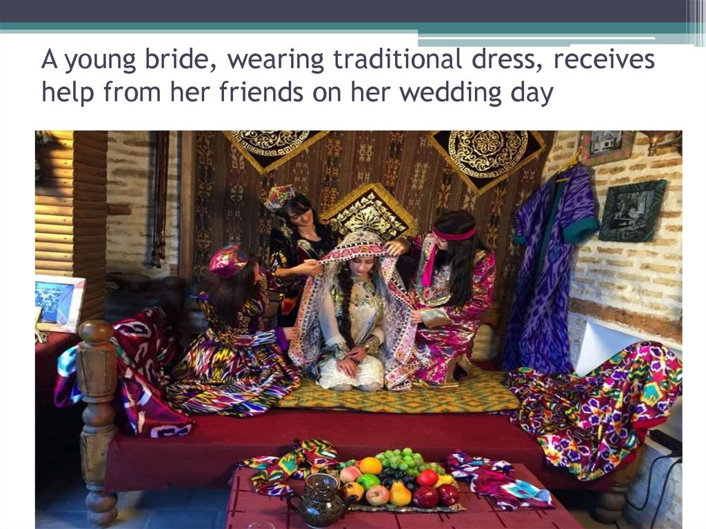 A young bride, wearing traditional dress, receives help from her friends on her wedding day